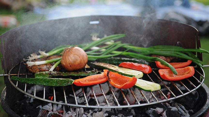 Verschiedenes Gemüse und etwas Fleisch liegt auf einem Grill.
