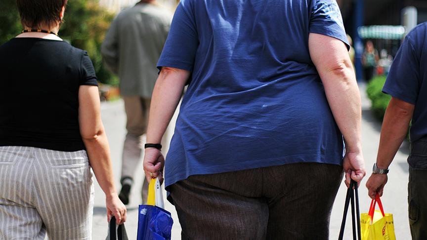 Eine übergewichtige Person trägt Einkaufstüten.