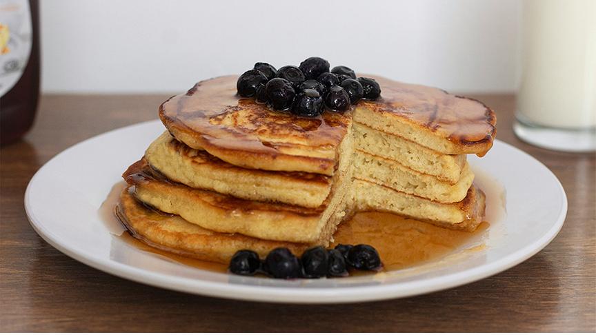 Pancakes gestapelt und mit Ahornsirup und Heidelbeeren ergänzt