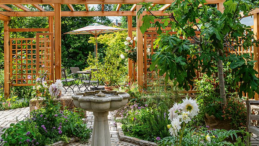 Klassischer Brunnen im Kräutergarten, im Hintergrund eine Pergola als Verbindung. (Schöner Gärten)