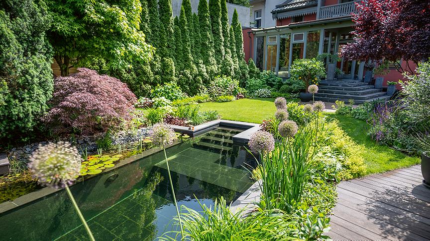 Großstadt-Idyll am Wasser - der Schwimmteich passt mit seinen edlen Natursteinplatten zum historischen Wohnhaus. (PGG Potsdamer Gartengestaltung GmbH)