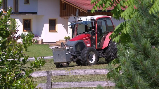 Ein roter Traktor fährt über eine Wiese.