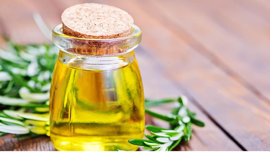 Ein kleines Glas Öl mit Korkdeckel, drumherum liegen Rosmarinstängel