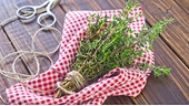 Thymianbündel auf einem karierten Tuch, daneben eine Schere