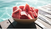 Schale mit hergeschnittenen Wassermelonen neben einem Pool