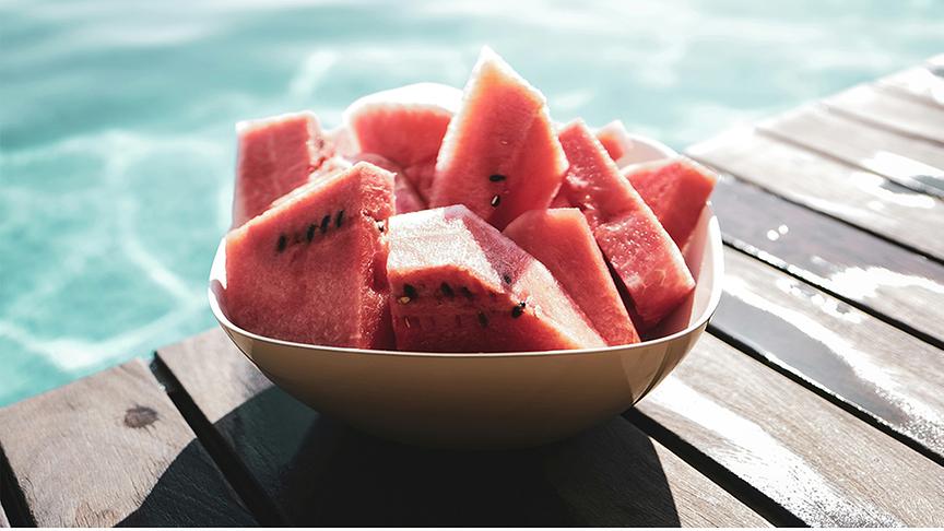 © Foto: Unsplash Schale mit hergeschnittenen Wassermelonen neben einem Pool