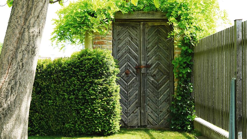 Der Garten ist gespickt mit vielen liebevollen Details, wie dieser Holztüre im antiken Stil.