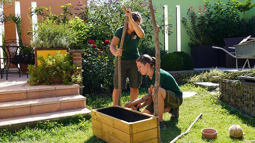 Die Gärtnerinnen der Garten Garten Tulln bauen ein bewachsenes Spalier aus Schnittgut.