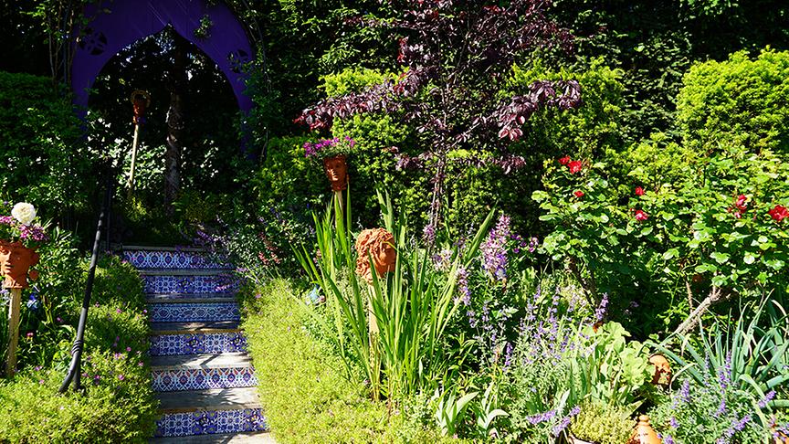 Eine Treppe mit marokkanisch angehauchten Mosaik-Fliesen führt durch das hügelige Land.
