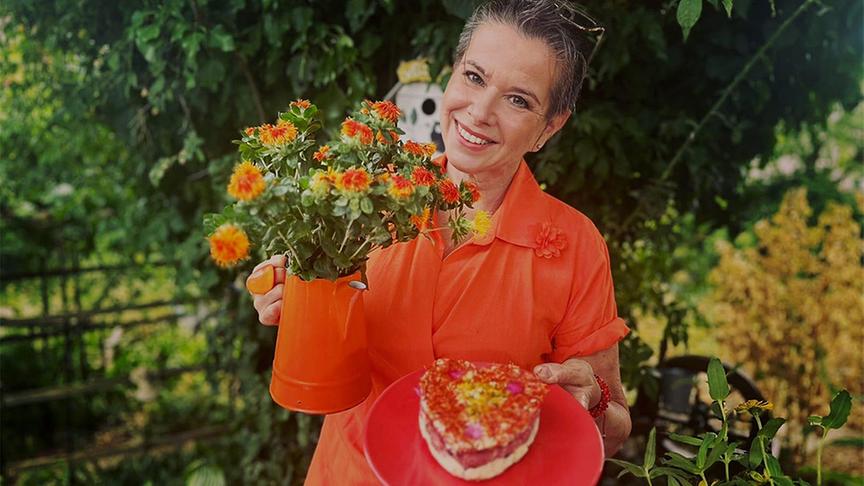 Uschi gestaltet aus Kräuterbutter, Färberdistelblüten, essbaren Sommerblüten und einem Docht eine essbare Sonnenbutter-Kerze für ein spätsommerliches Fest.