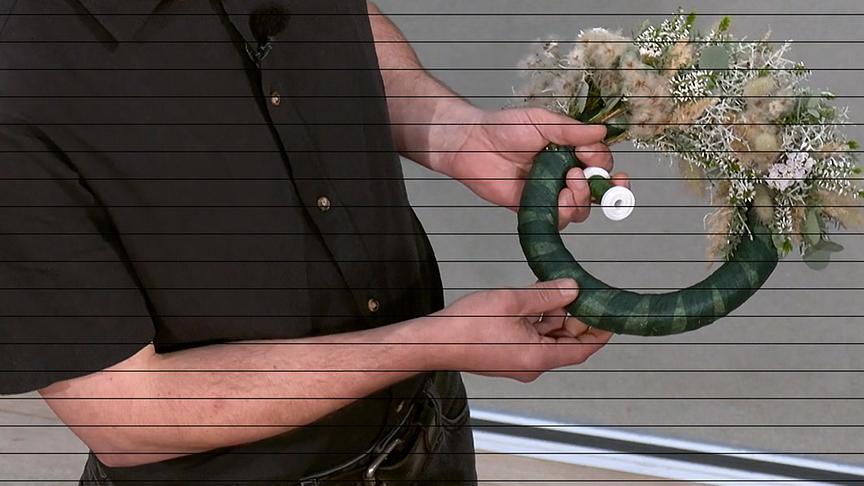 Strohkranz mit Herbstblumen, halb umwickelt.