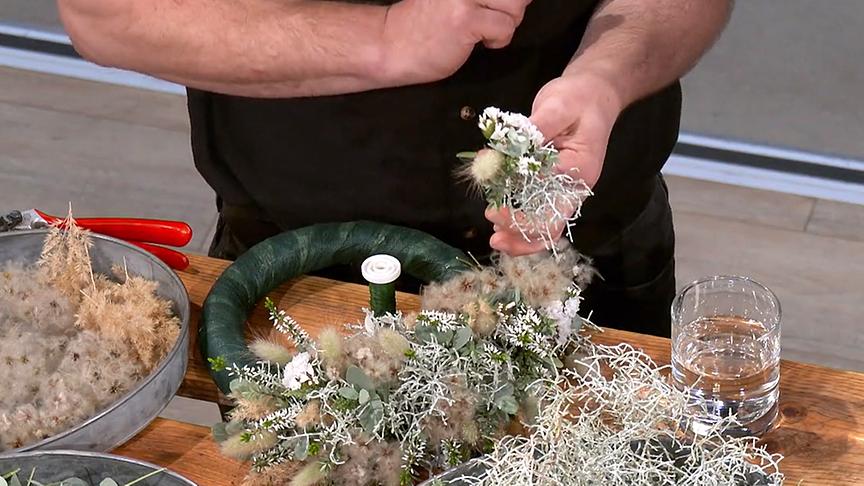 Karl Schick fasst das florale Material zu kleinen Büscheln zusammen.