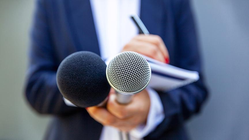 Ein News-Reporter hält zwei Mikrofone.