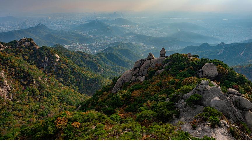 © Foto: Unsplash Weitläufige Panoramaaufnahme des Bukhansan-Nationalparks in Südkorea bei Dunst.