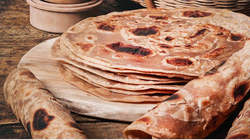 Chapati - Kenianisches Fladenbrot auf einem Holzbrett übereinander gestapelt und daneben aufgerollt.
