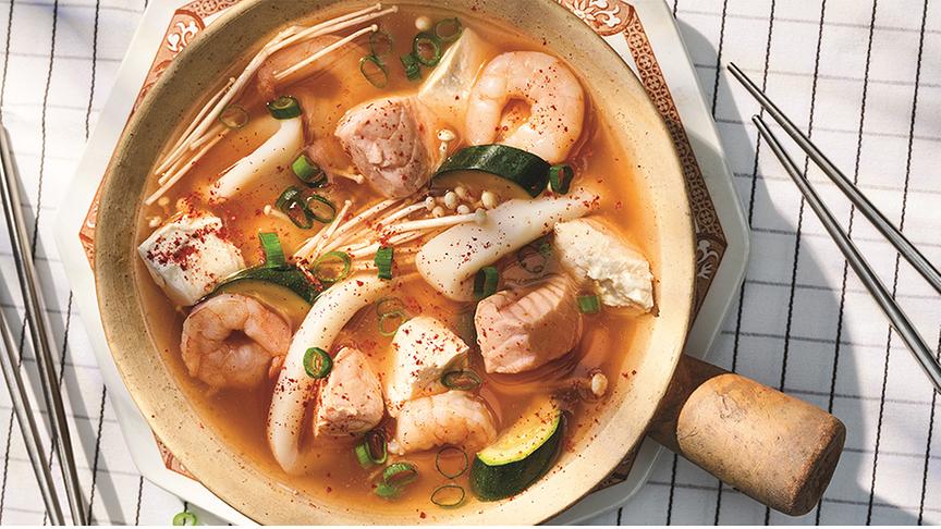 © © DK Verlag/ Daniel Herrmann-Zoll Hotpot mit Seidentofu in einer Schale auf karierter Tischdecke auf der auch Stäbchen liegen.