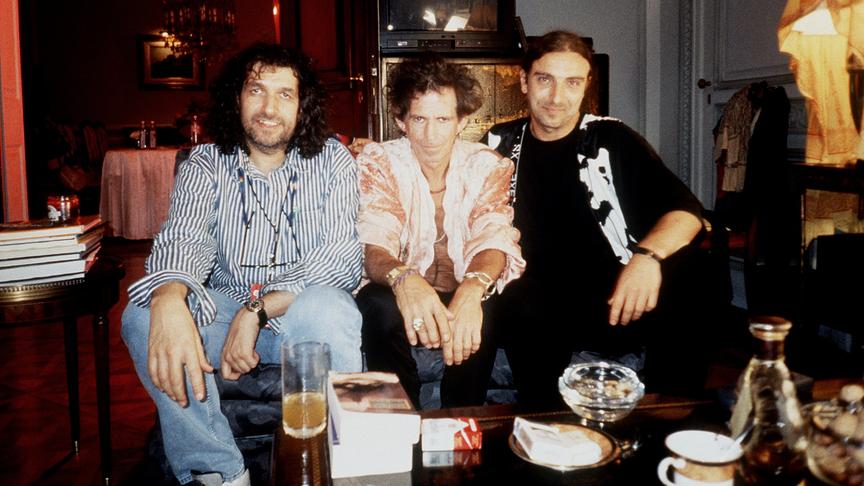 Hannes Rossacher, Keith Richards und Rudi Dolezal sitzen dicht nebeneinander auf einer Bank.