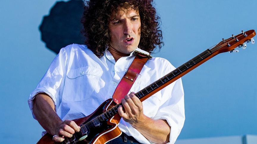 Mann mit braunen Locken spielt Gitarre, im Hintergrund das Live Aid Logo