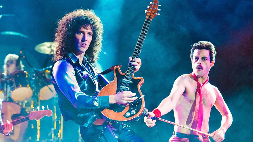 Zwei Männer, mit Gitarre und Mikrofon, performen auf einer Bühne vor Publikum