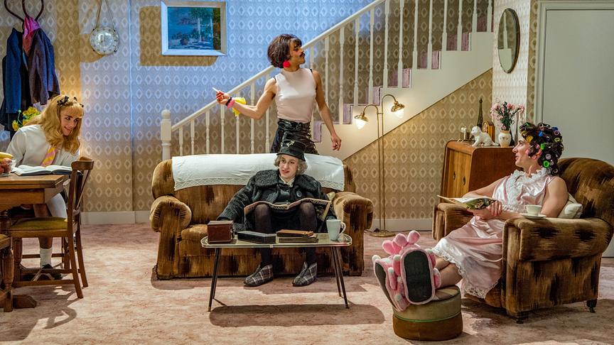 Mehrere Männer als Frauen verkleidet in einem Wohnzimmer