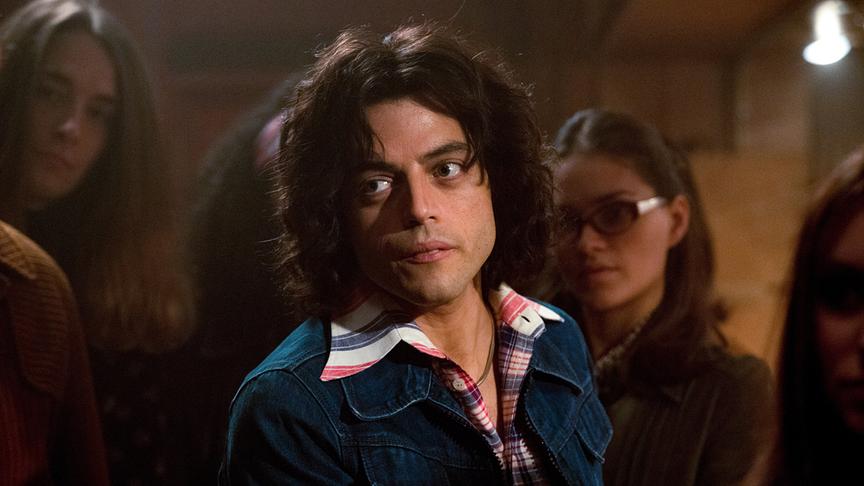 Mann mit braunen Locken vor einer Gruppe von Personen