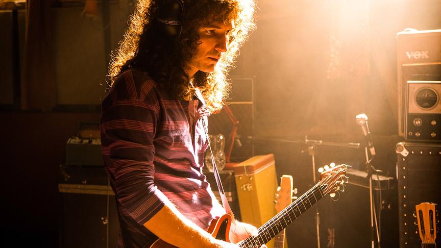 Mann mit langer Lockenmähne spielt Gitarre