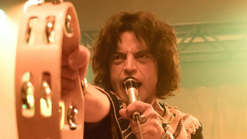 Mann mit Mikrophon hält Tamburin vor sich gestreckt