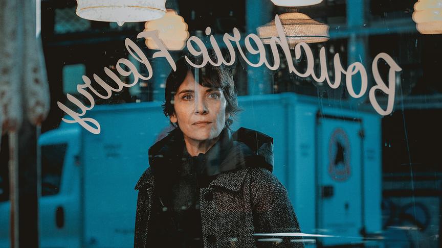 Eine Frau blickt von draußen durch ein Schaufenster hinein.