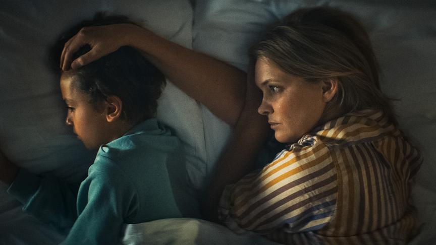 © Foto: ORF/ProSieben/LEONINE Studios Eine Frau liegt im Dunklen hinter einem Jungen im Bett und hat dabei die Hand auf seinen Kopf gelegt.