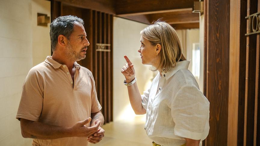 © Foto: ORF/ProSieben/LEONINE Studios Eine Frau hebt erzürnt ihren Fingen, ihr gegenüber steht ein Mann. Beide scheinen im Gang eines Hotels zu stehen.