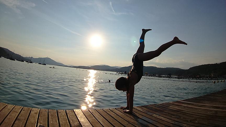 © Thomas Singer Tochter Laura (6 Jahre) schlägt ein Rad über den Steg ins Wasser, im Hintergrund der Pyramidenkogel bei Sonnenuntergang. (Thomas Singer)