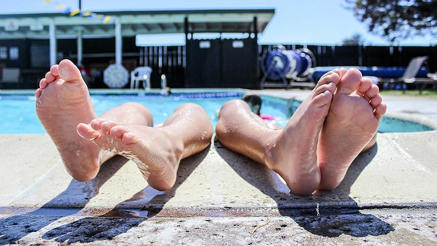 Zwei Paar Füße ragen aus dem Pool