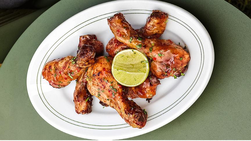 Smoky Drumsticks mit Limetten-Honig-Glasur auf einem Teller mit Limettenscheibe