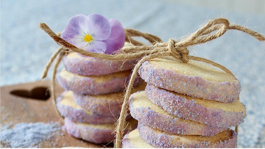 Tante Emmas Mürbeteigplätzchen mit lila Veilchenzucker in kleine Pakete geschnürrt und mit einem Veilchen verziert.