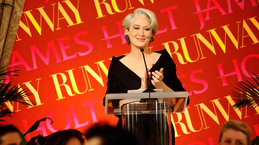 Frau in Abendgarderobe auf einer Bühne hinter einem Stehpult