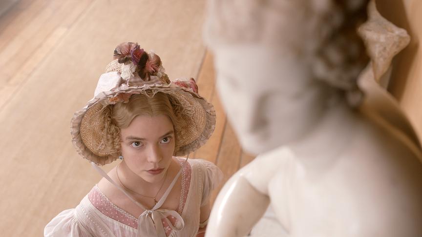 Eine Frau blickt nach oben, um eine weiße Statue zu betrachten.