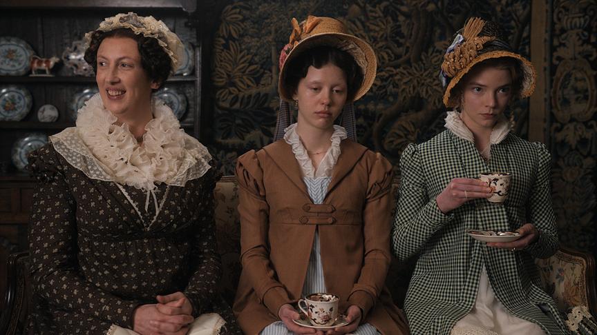 Drei Frauen sitzen nebeneinander, die zwei Frauen rechts blicken eher gelangweilt und besorgt, während die Frau links lächelt.