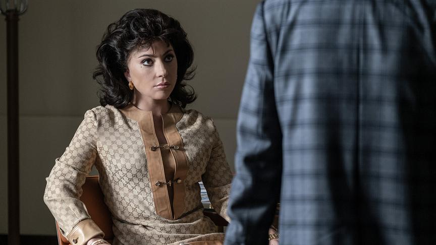 Eine Frau auf einem Stuhl sitzend und zu einem Mann aufblickend