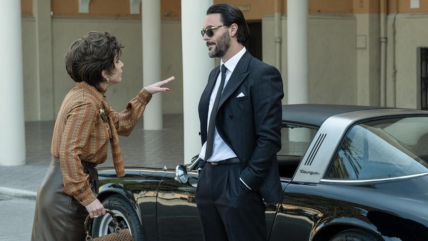 Eine Frau gestikuliert zu einem Mann, der an einem Auto lehnt