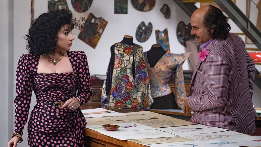 Eine Frau und ein Mann an einem Tisch mit Kleidungsentwürfend stehend