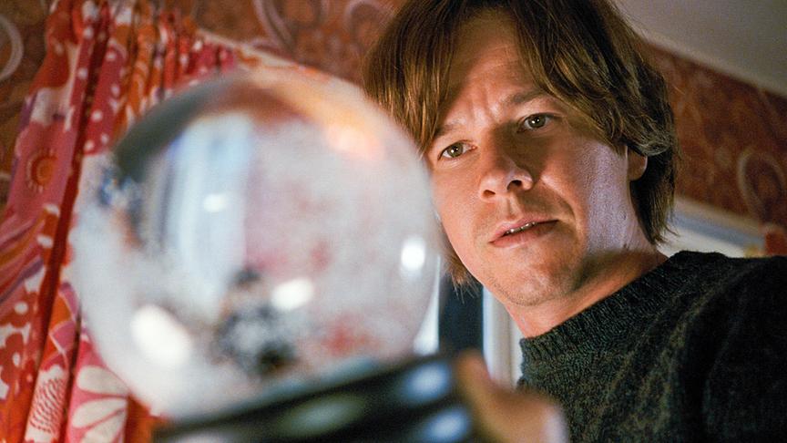 Mann schaut sich Schneekugel an.