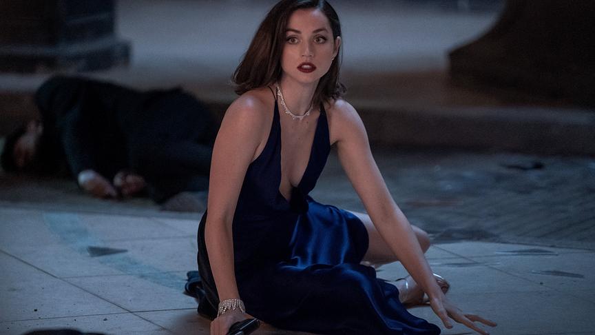 Frau in Abendgarderobe und Pistole in der Hand am Boden.