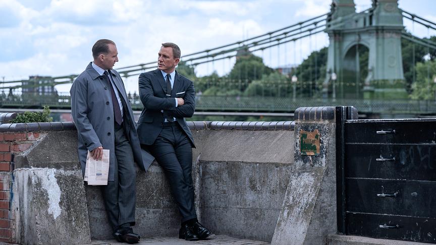 Zwei Männer in Anzug an eine Mauer gelehnt