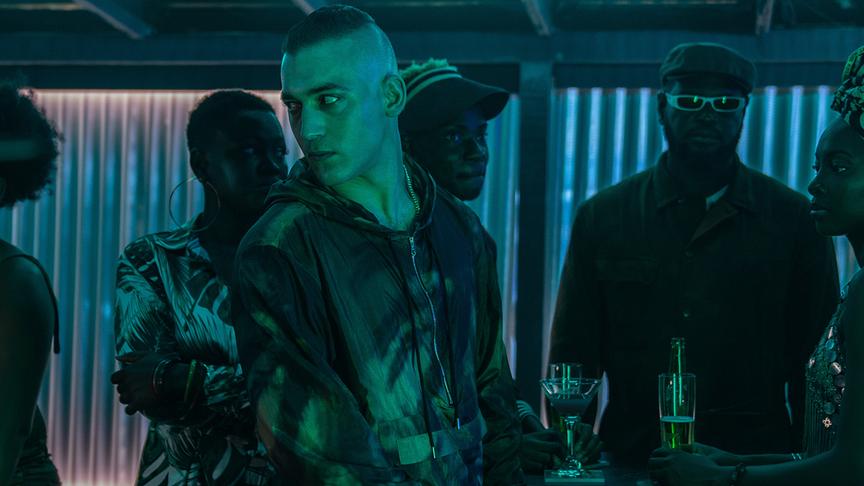 Mehrere Personen mit Drinks in einer dunklen Atmosphäre. 