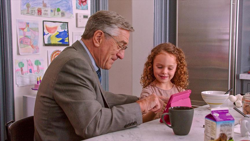 Ein Mann und ein kleines Mädchen tippen auf ein pinkes Tablet vor ihnen auf dem Tisch.