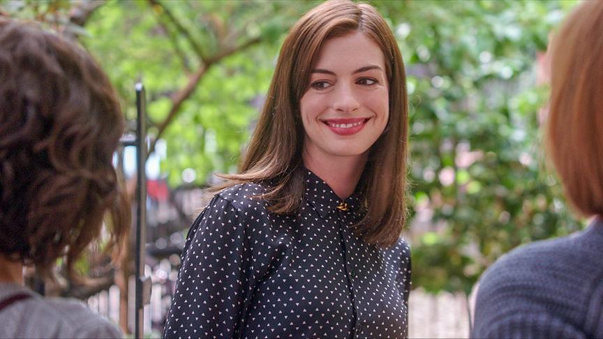 Eine Frau lächelt ihr gegenüberstehende Personen an