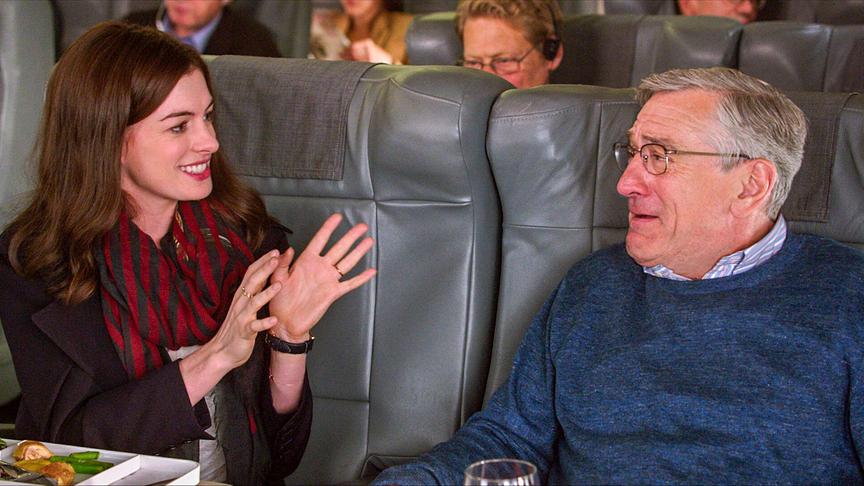 Eine Frau und ein Mann sitzen nebeneinander in Ledersitzen eines Verkehrsmittels.