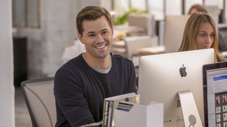 Ein Mann lächelnd an einem Schreibtisch