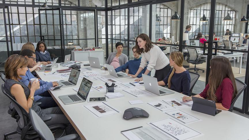 Mehrere Personen mit Laptops an einem großen Tisch