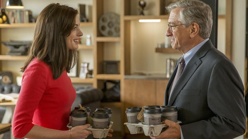 Eine Frau und eine Mann stehen sich gegenüber und halten jeweils mehrere Kaffeebecher in einer Kartonhalterung